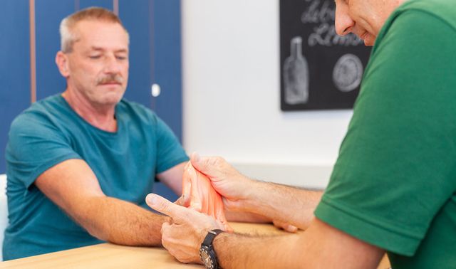 Der Ergotherapeut behandelt die Hand eines Patientens. 